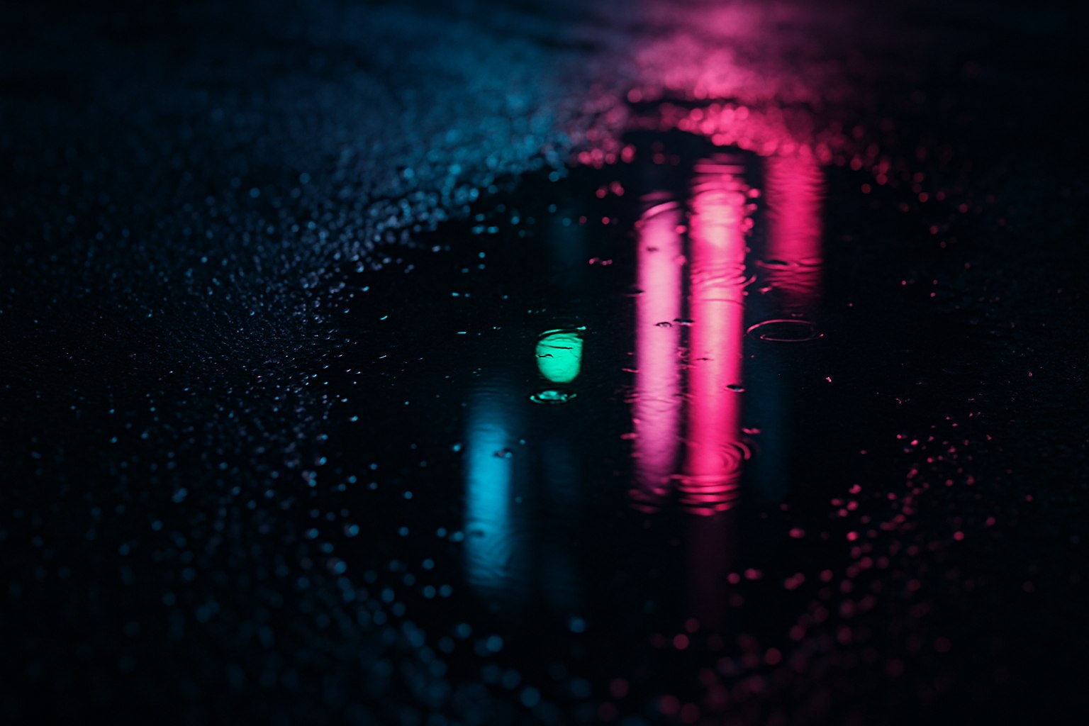 Close up of neon reflections in a puddle on wet asphalt at night