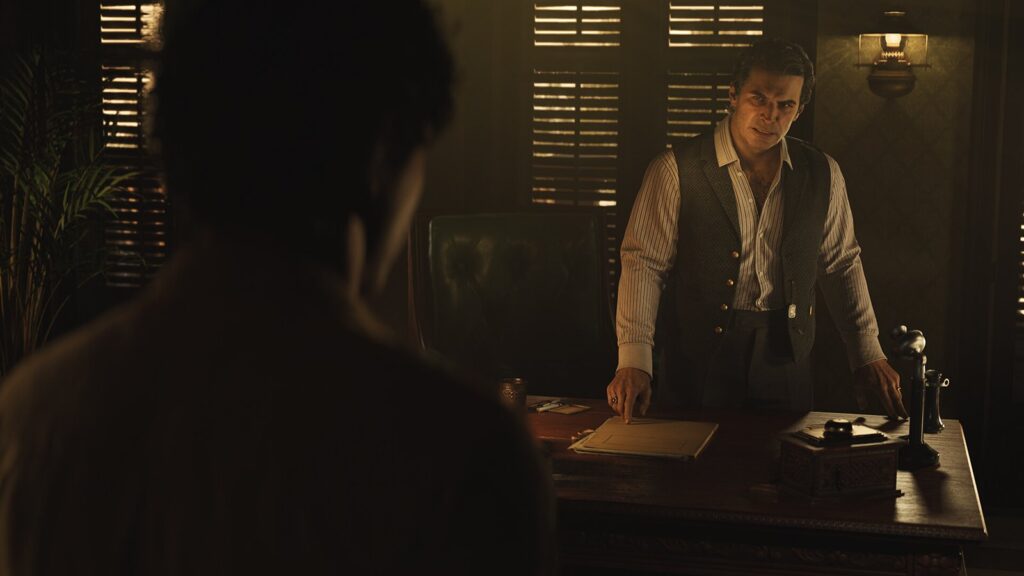 Enzo talking to the head of the family in a dark office