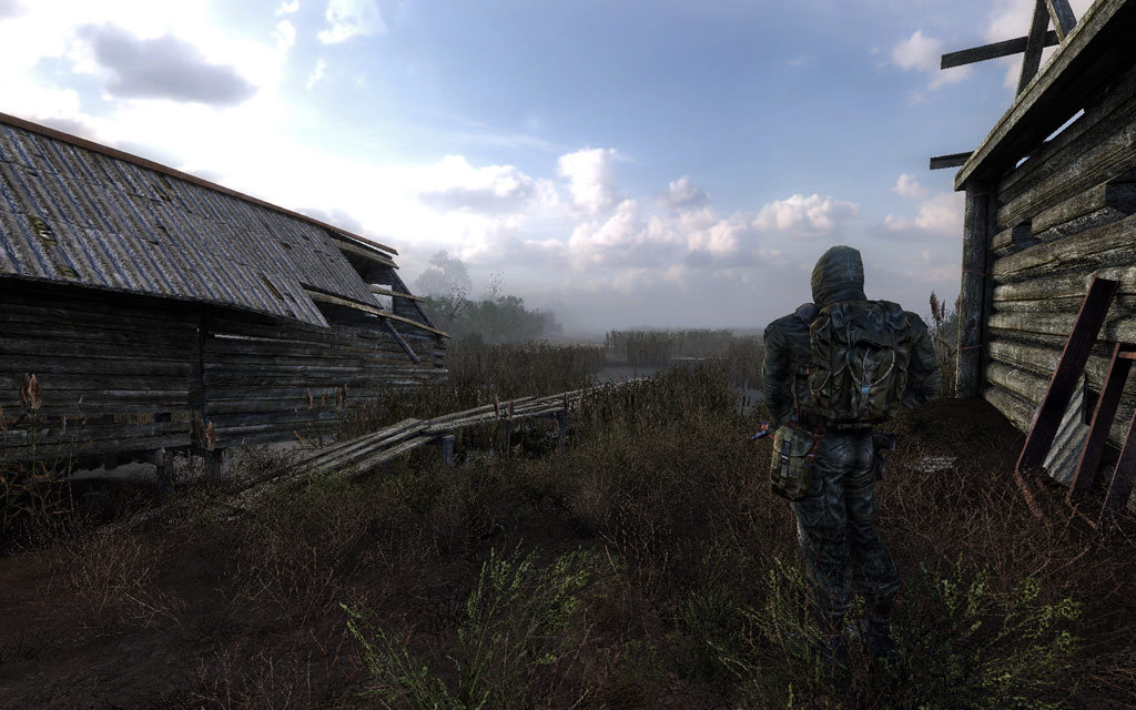 A lone stalker near wooden houses in the swamps in S.T.A.L.K.E.R. Clear Sky
