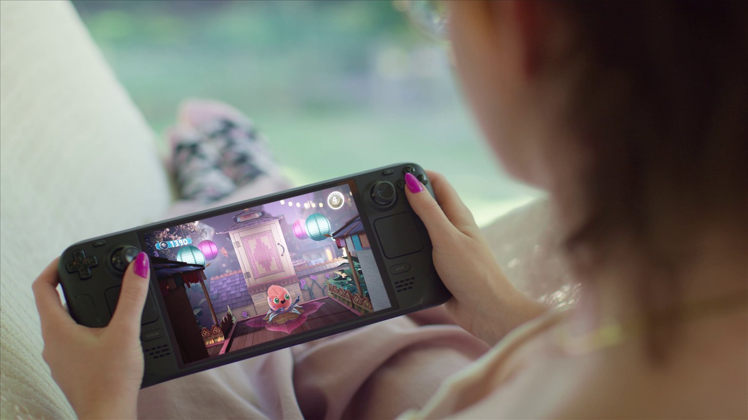 A person playing a game on a Steam Deck while sitting on a sofa