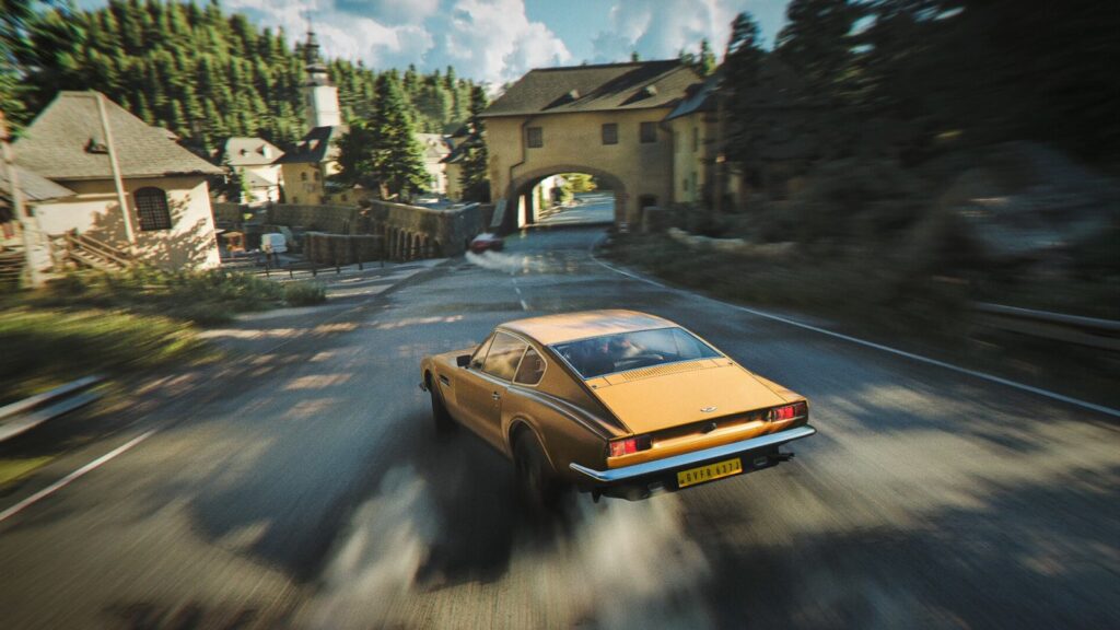 A car on a mountain road beside an old town