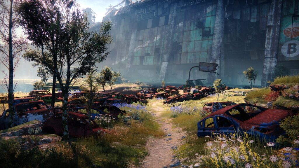 An overgrown scrapyard beside a ruined wall