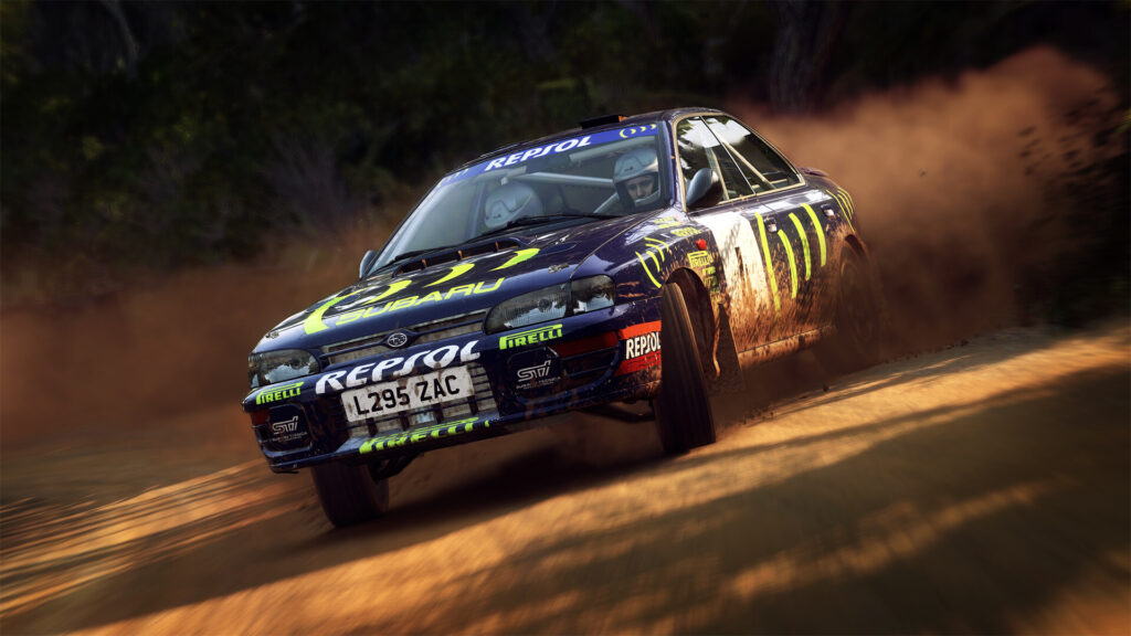 A Subaru Impreza in Repsol livery throws up dust on a gravel road at sunset