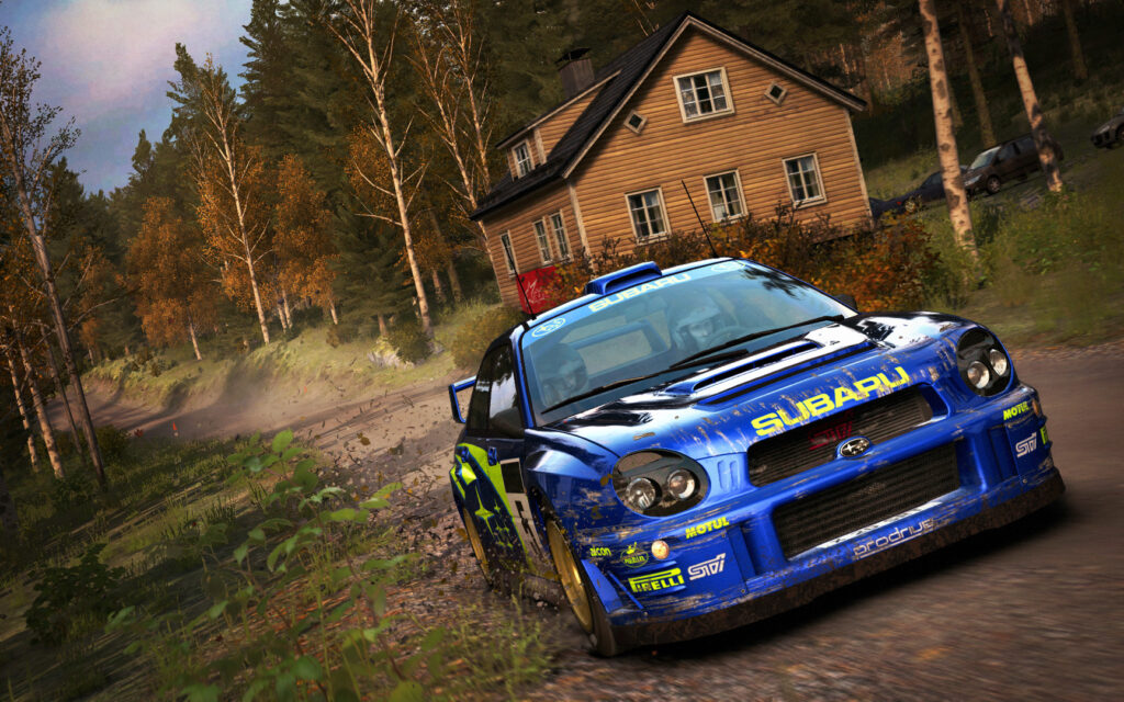 A blue Subaru Impreza on a gravel road next to a wooden house in the forest