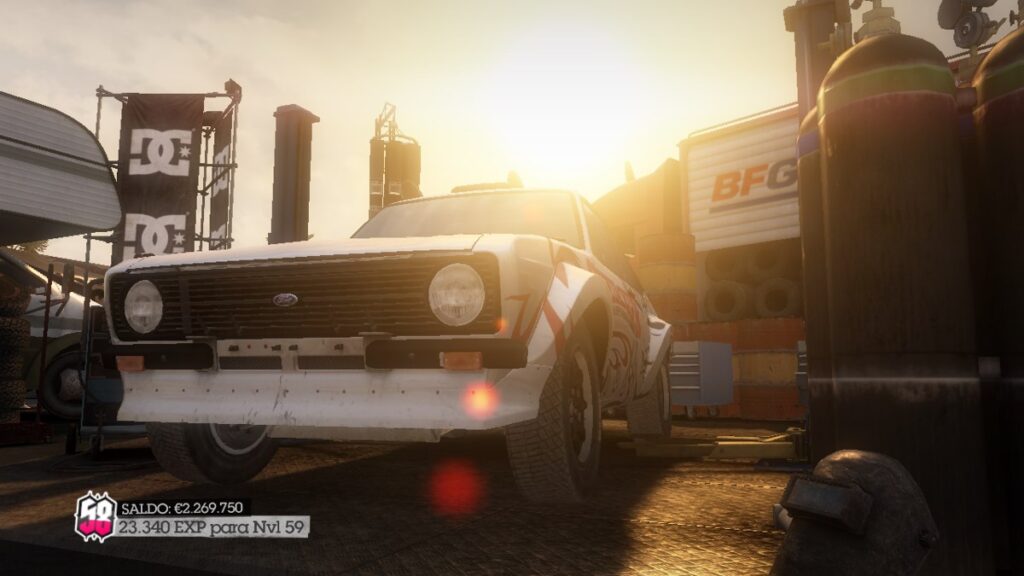 A white Ford Escort in the pits under bright sun, tyres and toolboxes around it