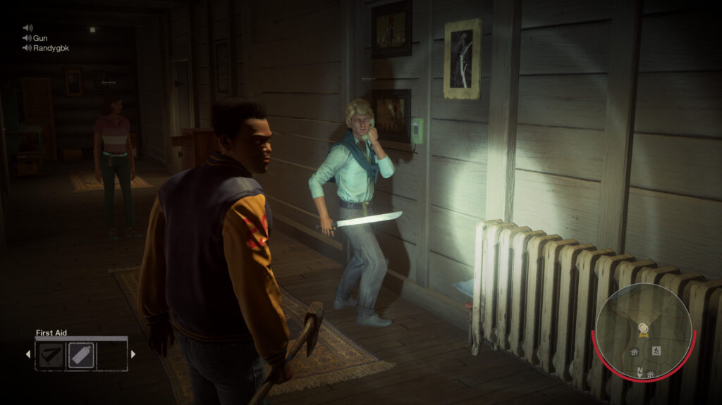 A counselor in an orange jacket and another with a knife walk through a dark cabin with a flashlight